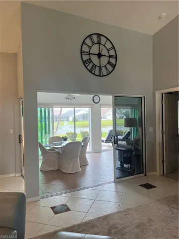 Vaulted ceiling, sliding glass doors, ceramic tile flooring, and a screened enclosure overlooking a water feature