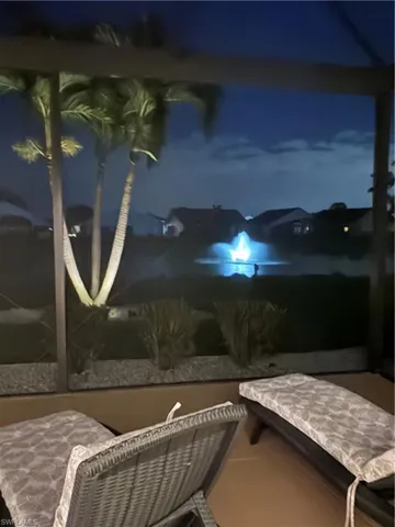 Screened-in outdoor living space with a paver patio and mature palm trees