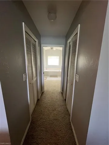 Carpeted hallway featuring louvered bi-fold doors and light gray painted walls
