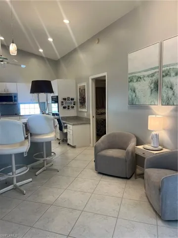 Open-concept living area featuring vaulted ceilings with recessed lighting, light-toned tile flooring, and a built-in desk area with a light-toned countertop