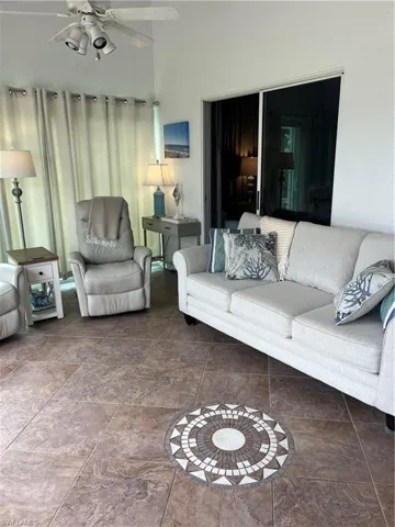 Spacious room featuring vaulted ceilings, a ceiling fan with integrated lighting, and large format floor tiling with a decorative mosaic insert