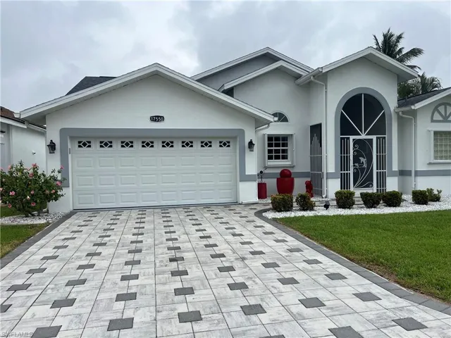 Beautiful home featuring a patterned paver driveway and an arched entry with decorative security door water features at the front and rear of the home.