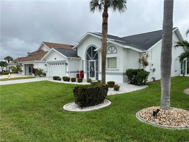 White stucco exterior with a dark shingle roof and a two-car garage