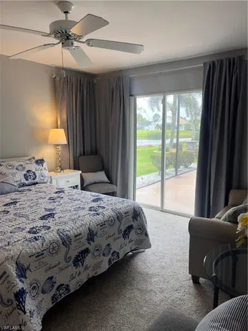 Bedroom featuring wall-to-wall carpeting, sliding glass doors, and a ceiling fan
