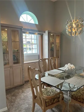 Dining area featuring a high arched window, built-in display cabinetry with glass fronts, and a contemporary spherical pendant light fixture