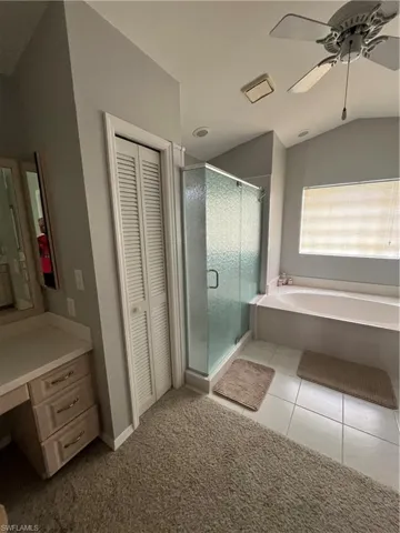 Bathroom featuring a glass-enclosed shower, built-in soaking tub, and a vanity area with integrated storage