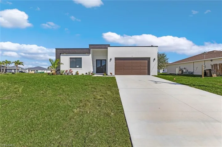 Contemporary house with stucco siding, an attached garage, driveway, and a front yard