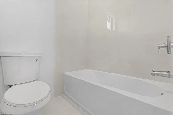 Bathroom featuring tile patterned floors, toilet, and a tub to relax in