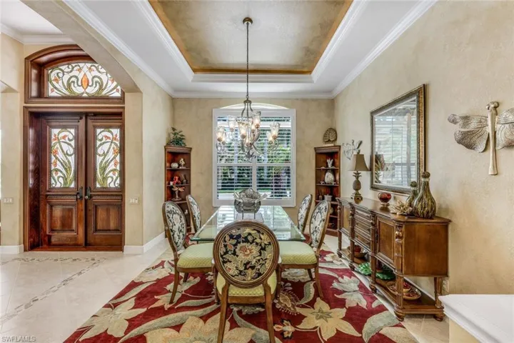 coffered ceiling featuring plenty of natural light, ornamental molding, indirect uplighting in the tray ceiling, and beautiful chandelier