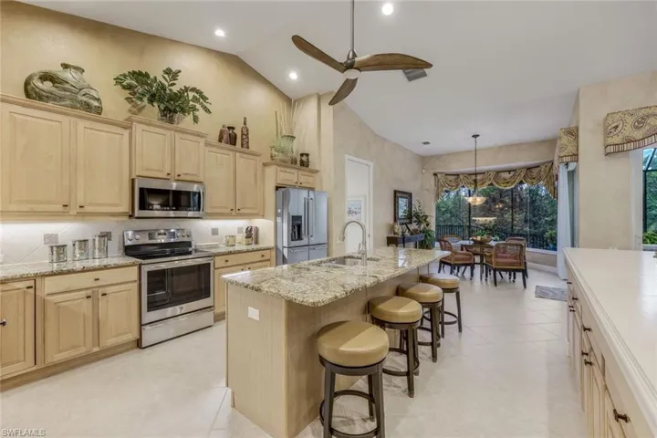 Great room kitchen with high vaulted ceiling, a kitchen island with sink, beverage refrigeration and dishwasher