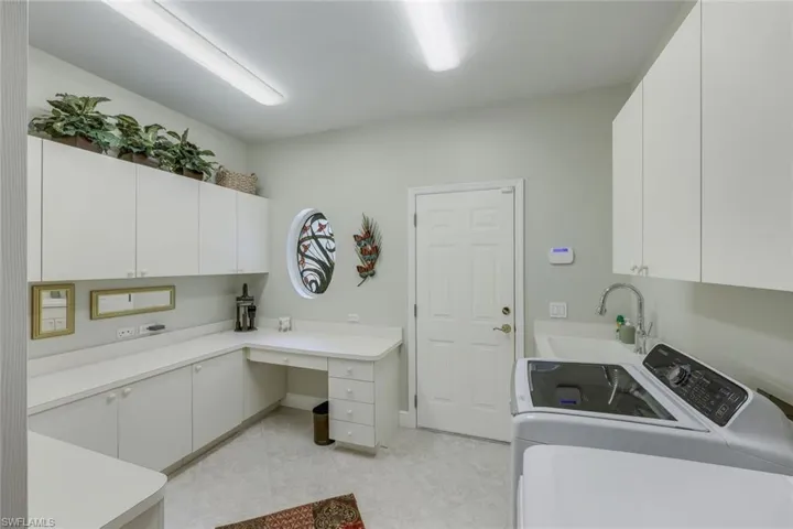 Laundry room featuring washer and clothes dryer, sink, light tile floors, plentynof storage and countertop space