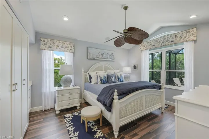 Guest suite with dark wood-style tile flooring, multiple windows, and ceiling fan