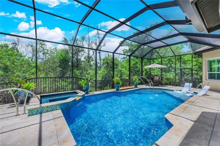 View of pool lanai and quick heat spa with waterfall featurefeature