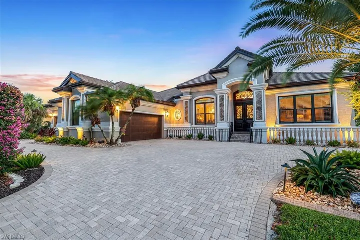 View of front of property with spacious pavered circle drive and 2 side load garage accesses (one to the far left).