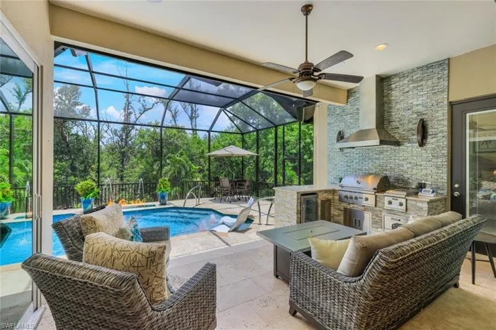 Fantastic covered lanai featuring outdoor kitchen glass backsplash accent wall, sconces  new built in grill and 2 burner cooktop with beverage cooler.Bar with granite and flagstone surround.