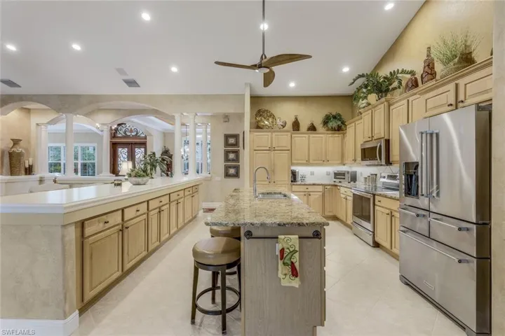 Kitchen with custom wood cabinets, breakfast bar, light tile floors, sink, and new appliances with stainless steel finishes