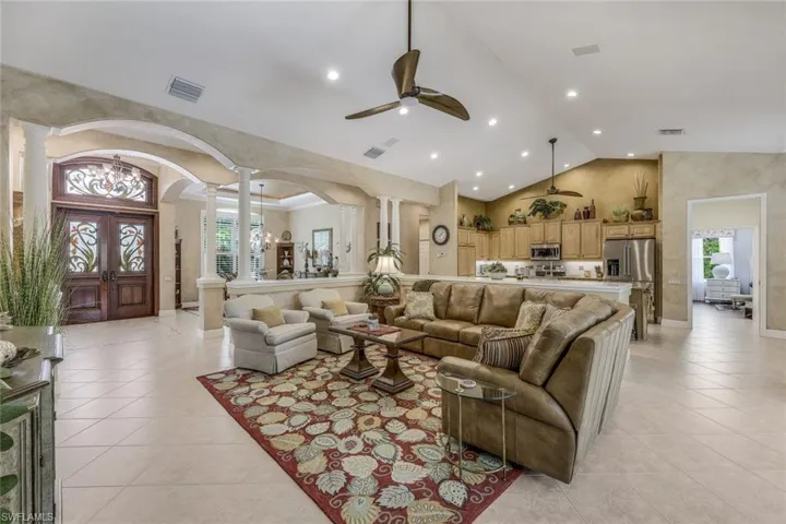 Living room with high vaulted ceiling, ceiling fan, light tile floors, and ornate columns. Every room has Sonos sound automation both inside and out.