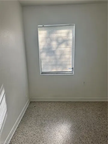 Empty room featuring speckled floor and baseboards