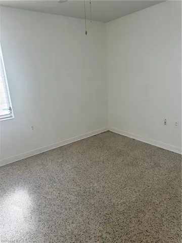 Empty room with baseboards and speckled floor