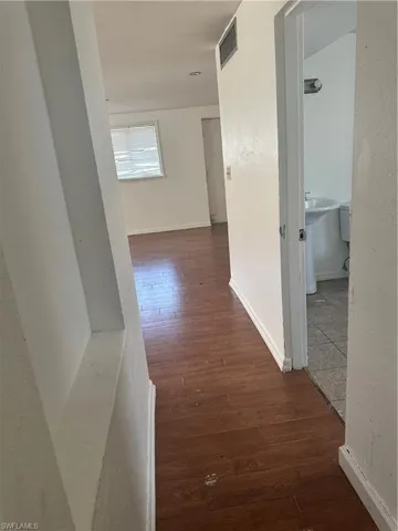 Corridor with visible vents, baseboards, and wood finished floors