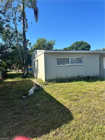 View of side of property with a lawn and stucco siding