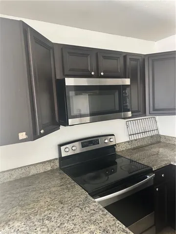 Kitchen with stove and dark cabinets