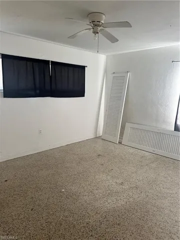 Empty room with baseboards, ceiling fan, and speckled floor