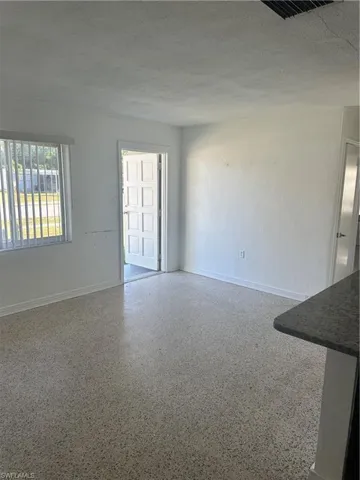 Spare room featuring speckled floor, baseboards, visible vents, and a textured ceiling