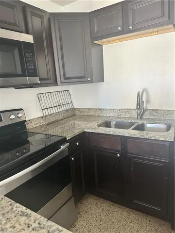 Kitchen featuring range, a sink, light speckled floor, and light stone counters