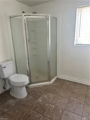 Full bath featuring baseboards, toilet, and a shower stall