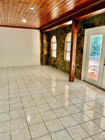 Unfurnished room with wooden ceiling, light tile patterned floors, and ornamental molding