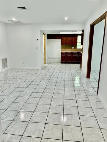 Unfurnished living room featuring light tile patterned floors and baseboards