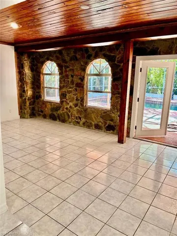 Unfurnished room with wooden ceiling, plenty of natural light, and light tile patterned floors