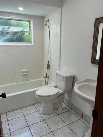 Full bath with shower / bathtub combination, a textured wall, and light tile patterned floors