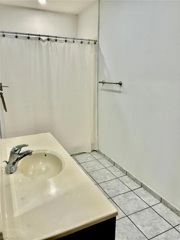 Bathroom featuring vanity, curtained shower, and light tile patterned flooring