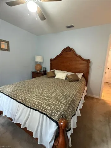 Carpeted bedroom with ceiling fan and baseboards