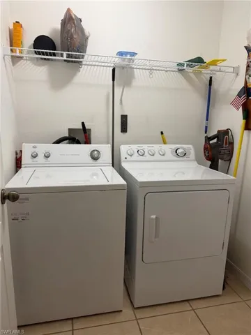Laundry area featuring light tile patterned floors and separate washer and dryer