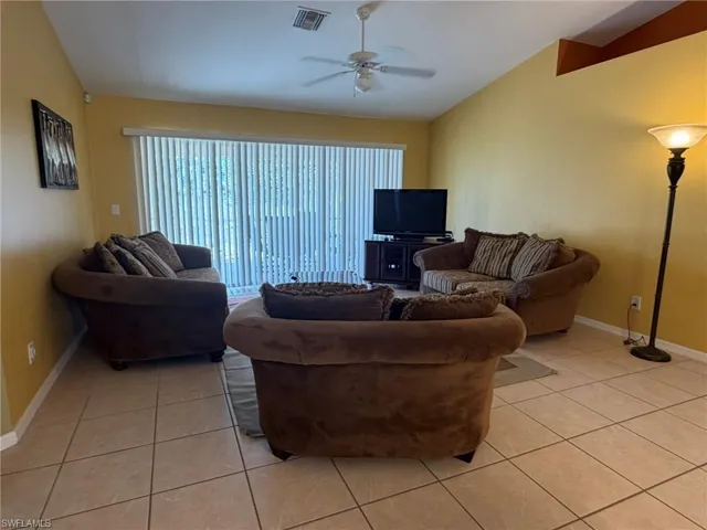 Living area featuring vaulted ceiling, ceiling fan, and light tile patterned floors