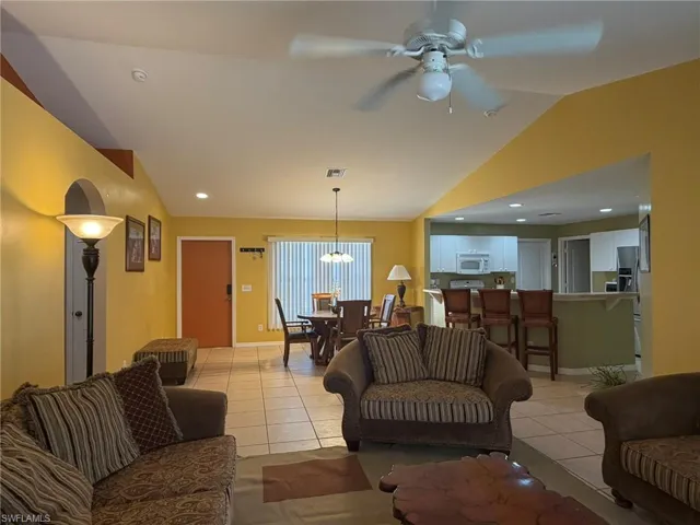 Living room featuring ceiling fan, lofted ceiling, light tile patterned floors, and recessed lighting