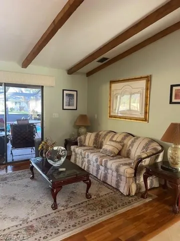 Living room with lofted ceiling with beams and light wood-type flooring