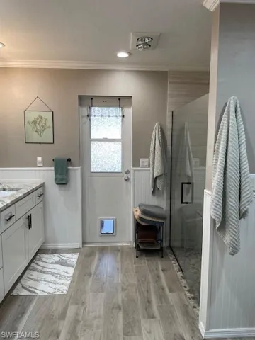 Bathroom featuring vanity, hardwood / wood-style flooring, an enclosed shower, and ornamental molding