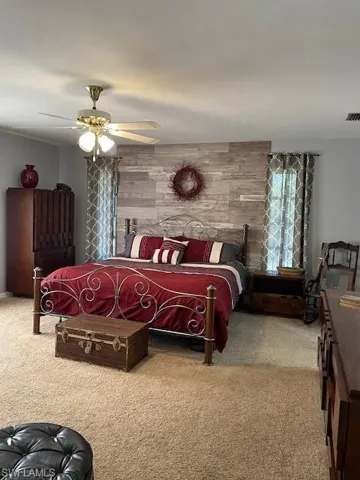 Carpeted bedroom with ceiling fan and wood walls