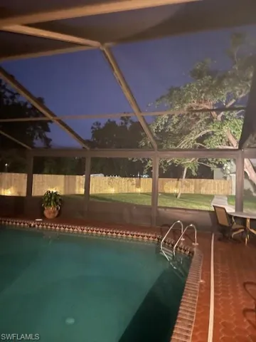 Pool at dusk featuring a lanai