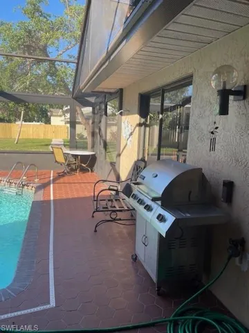 View of patio with a lanai, a fenced in pool, and grilling area