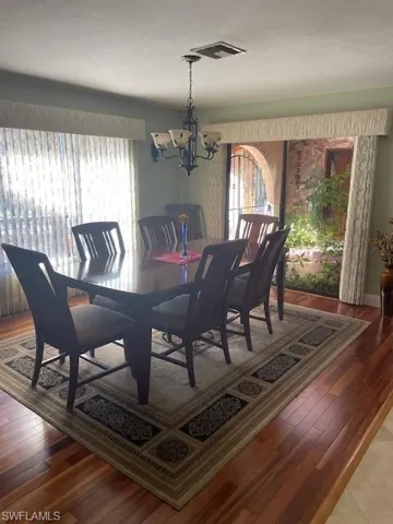 Dining space with hardwood / wood-style flooring and an inviting chandelier