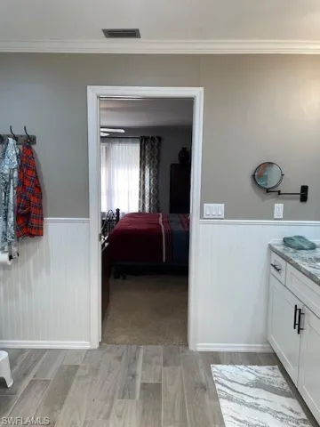 Bathroom with crown molding, vanity, and wood-type flooring