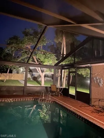 View of swimming pool featuring a lanai
