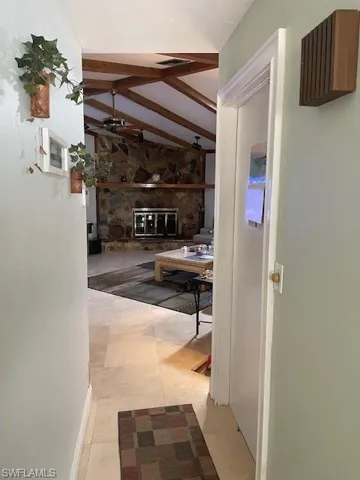 Corridor featuring vaulted ceiling with beams and light tile patterned floors