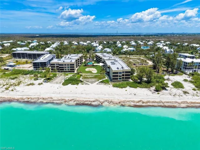 Beachfront property featuring multiple low-rise buildings, a sandy shoreline, and turquoise water