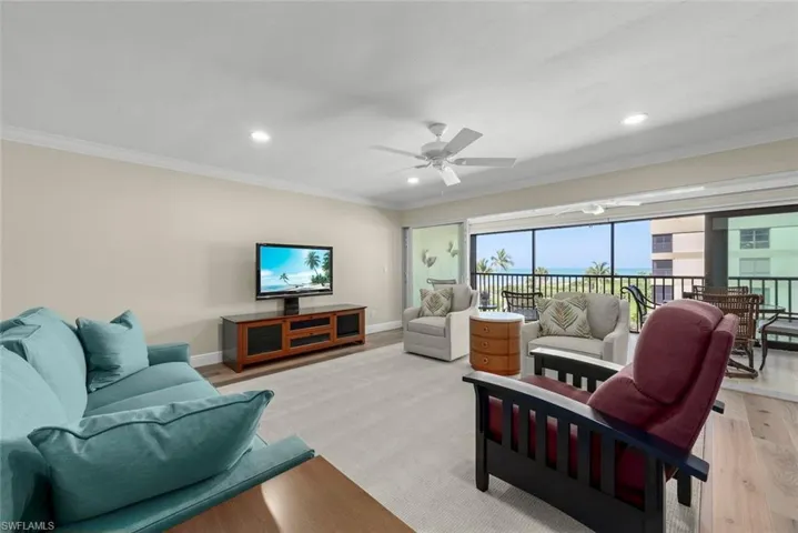 Living area featuring neutral wall tones, crown molding, and recessed lighting